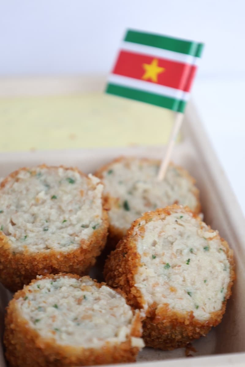 Portie crispy vleesworst in een bakje met een Surinaamse vlag
