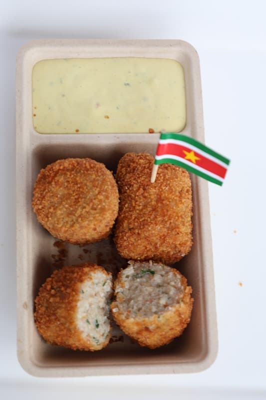 Portie crispy vleesworst met huisgemaakte saus en een Surinaamse vlag